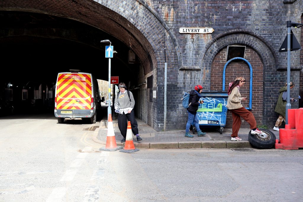 A group of people are making a field recording near a railway bridge on an industrial street in central Birmingham near Snow Hill Station