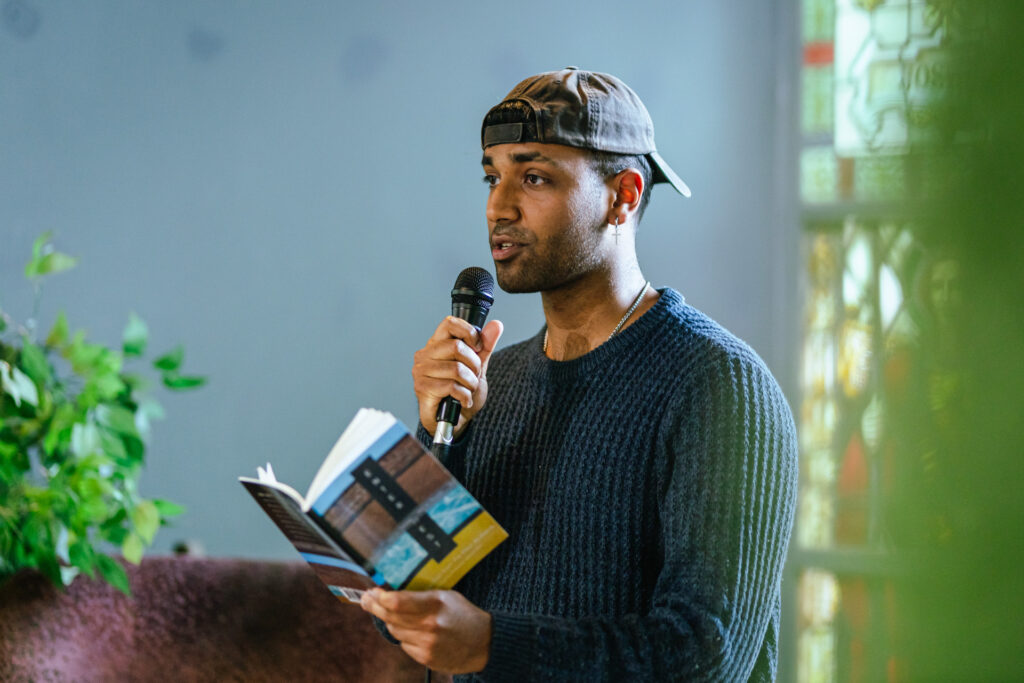 Vignesh performing poetry from a book into a microphone