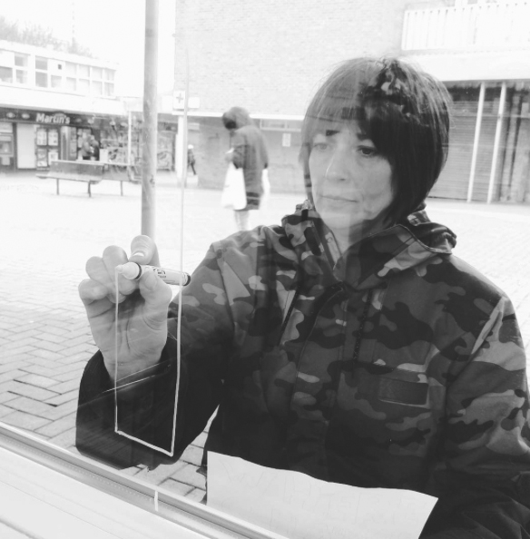 Black and white image of Jayne drawing on a glass window